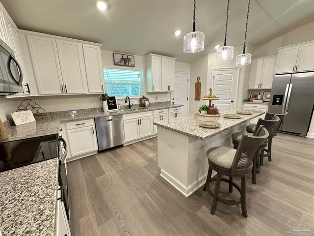 a kitchen with a sink a stove a refrigerator and chairs