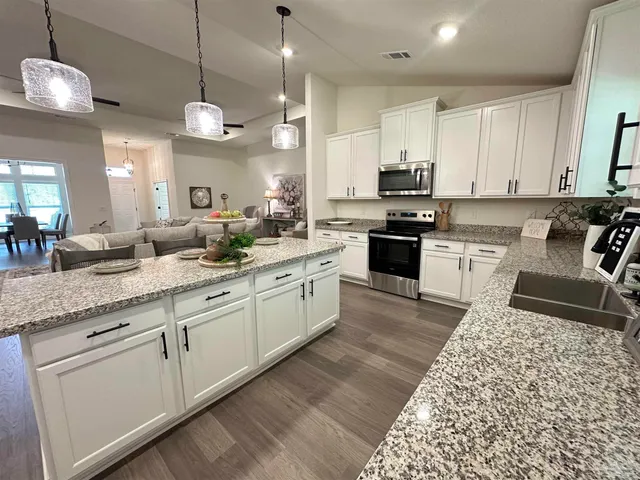 a large kitchen with stainless steel appliances granite countertop a stove a sink a oven a dining table and chairs with wooden floor