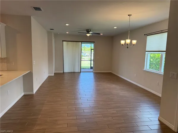 a view of an empty room with window and wooden floor