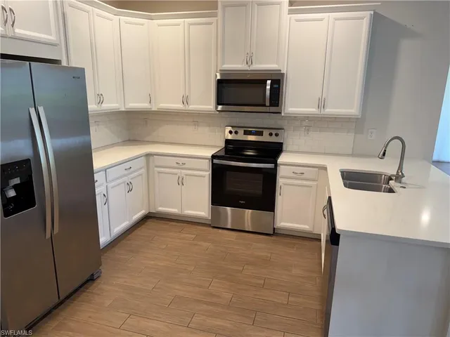 a kitchen with stainless steel appliances a stove a sink a microwave and cabinets