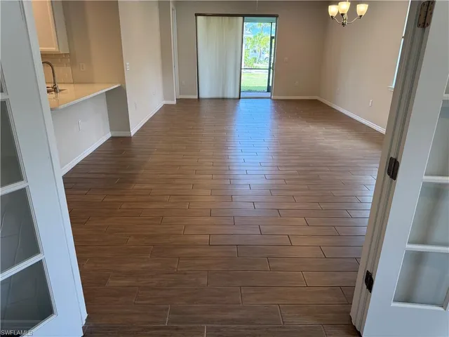 a view of hallway with window and wooden floor