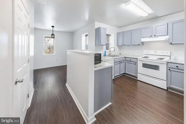 a kitchen with white cabinets appliances and wooden floor