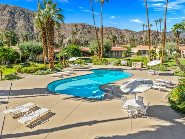 a view of a swimming pool with a lawn chairs under an umbrella