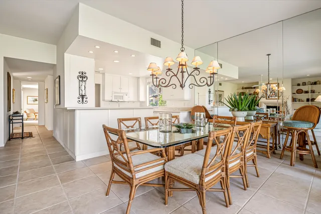 a dining room filled chandelier and kitchen view