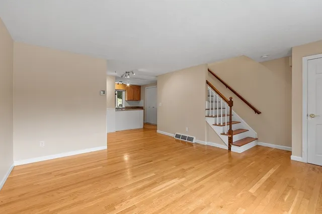 a view of an empty room with wooden floor and stairs