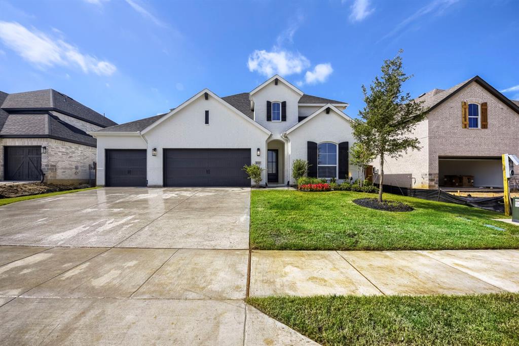 Two-story residence featuring a white stucco facade with black shutters, a two-car garage, and a concrete driveway
