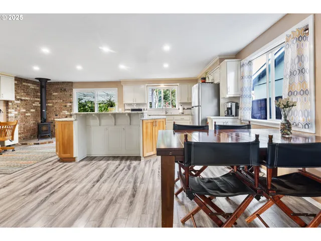 a kitchen with stainless steel appliances kitchen island granite countertop a dining table chairs and a refrigerator
