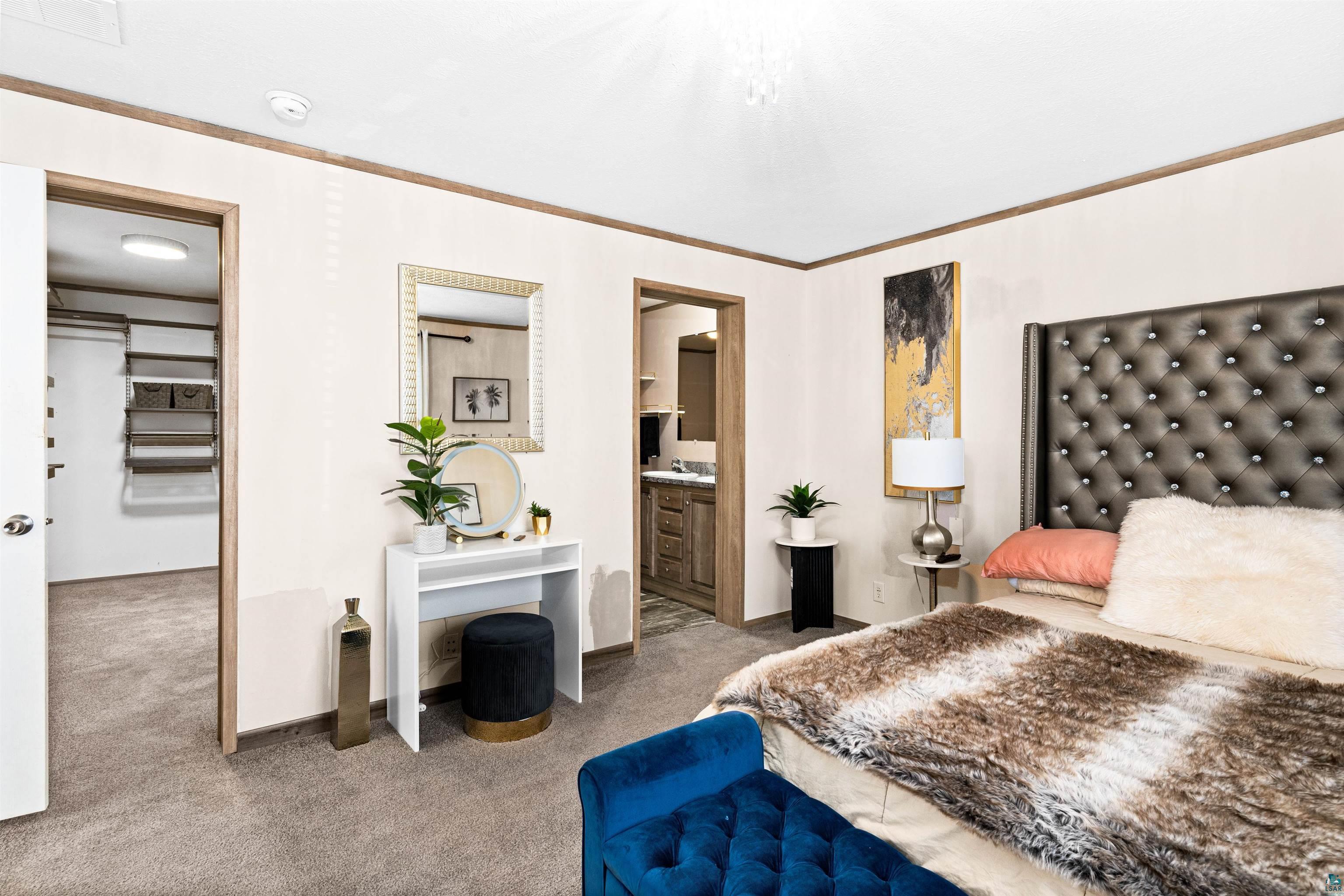 5562 Lavaque Road Duluth, MN 55803 - Photo 16 of 28 Bedroom with a spacious closet, ensuite bathroom, crown molding, and carpet flooring