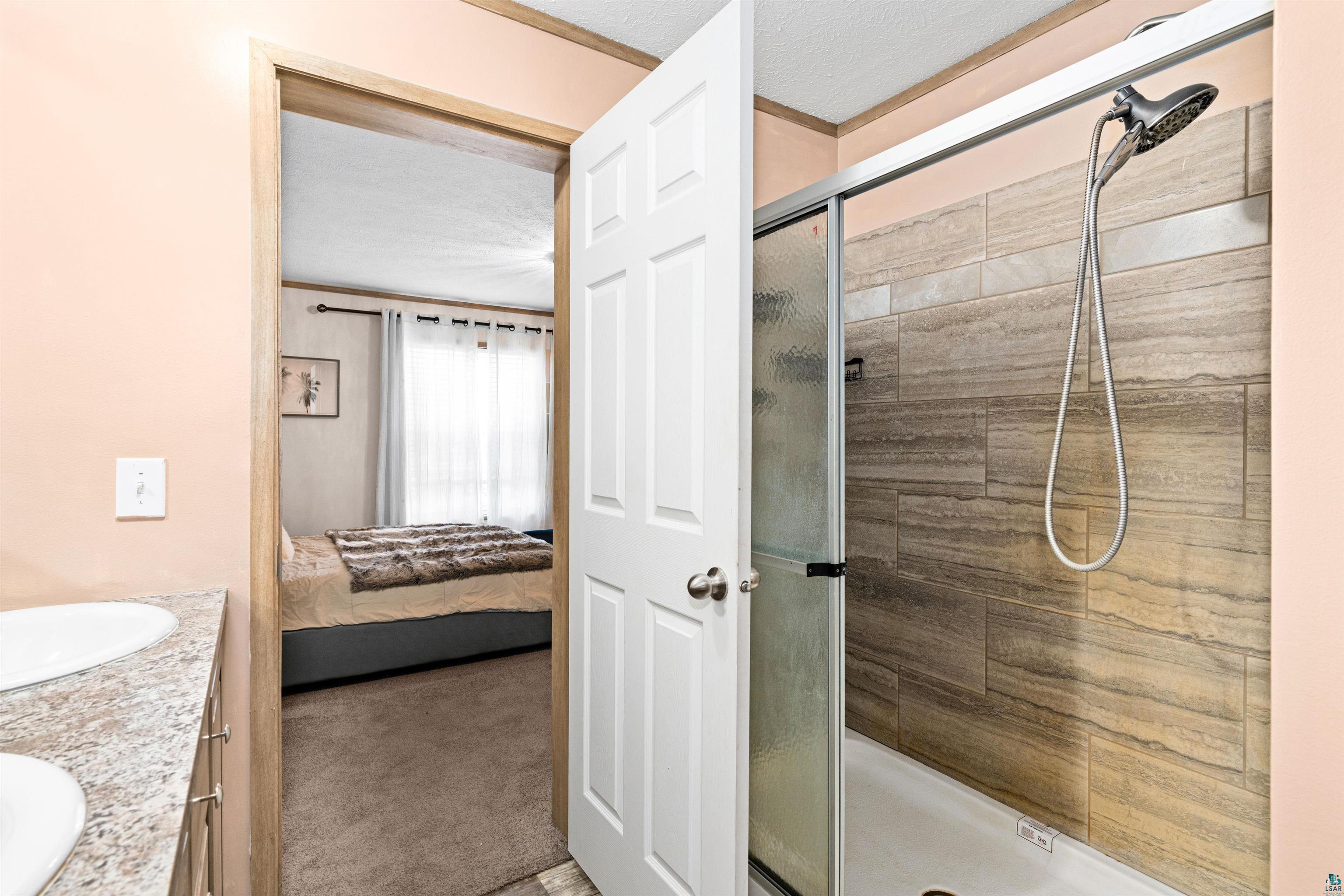 5562 Lavaque Road Duluth, MN 55803 - Photo 19 of 28 Bathroom with a shower with door, a textured ceiling, and vanity