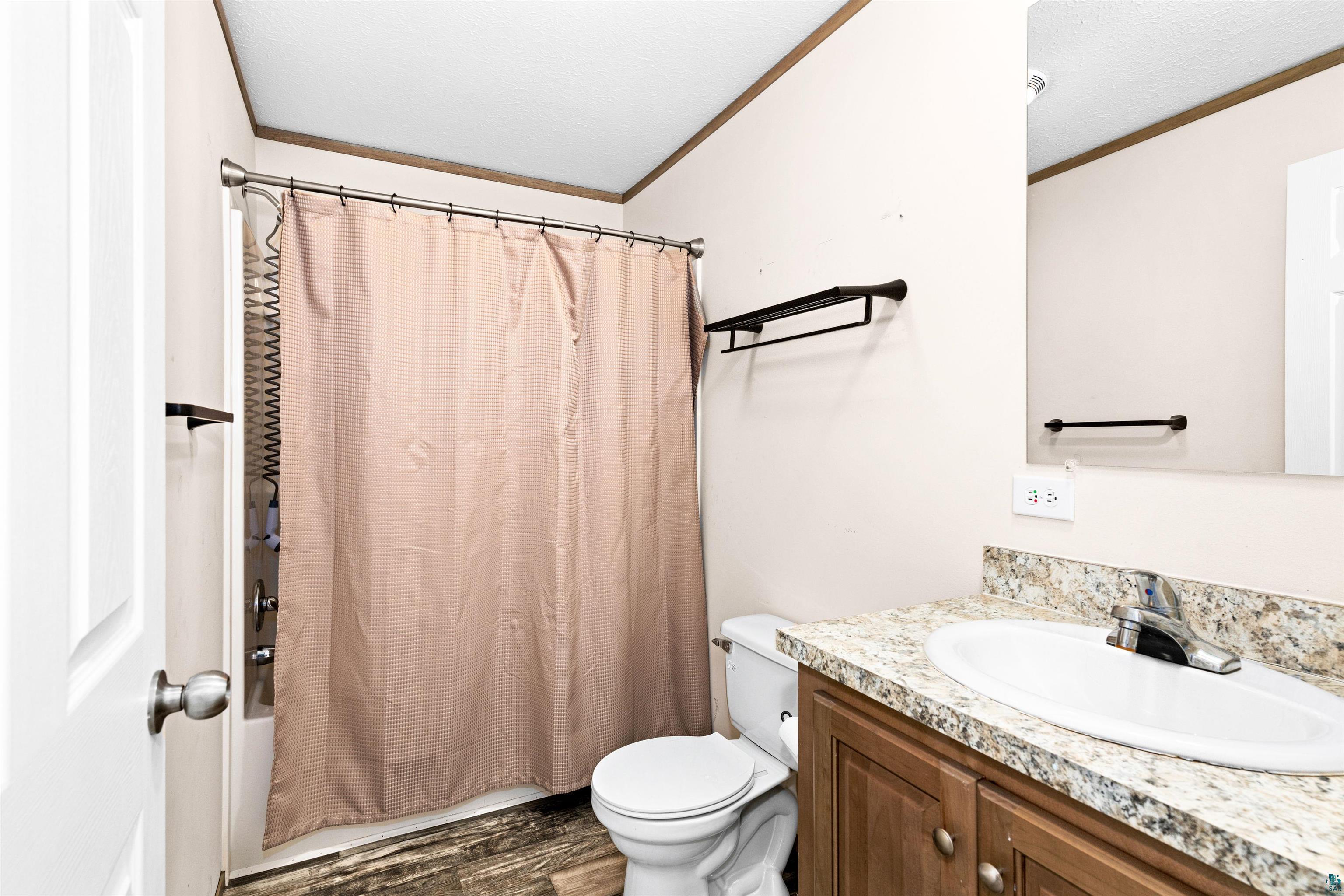 5562 Lavaque Road Duluth, MN 55803 - Photo 20 of 28 Full bathroom featuring shower / tub combo, hardwood / wood-style flooring, toilet, vanity, and crown molding