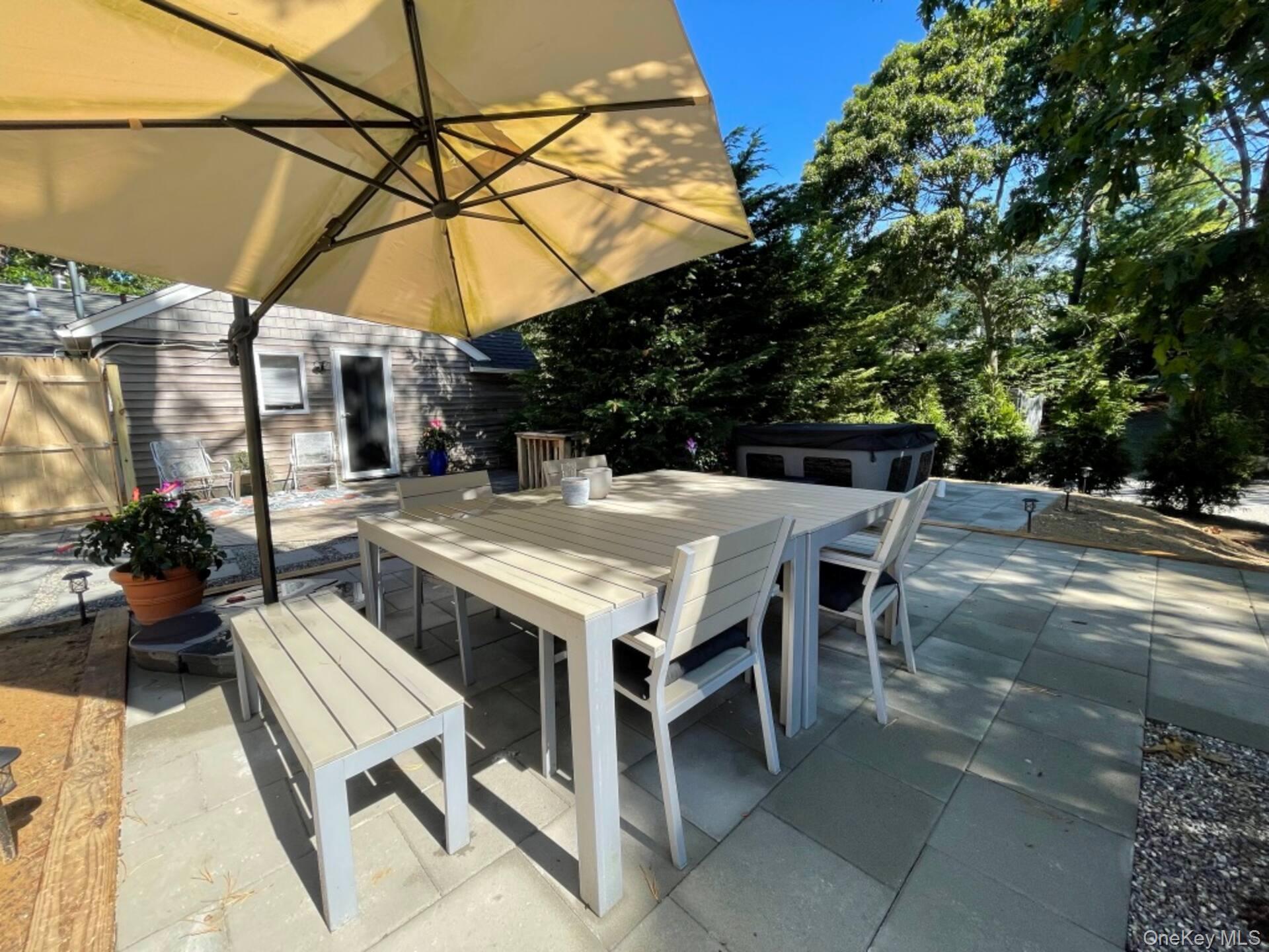 332 Canoe Place Road Southampton, NY 11968 - Photo 11 of 19 a patio with a table and chairs under an umbrella