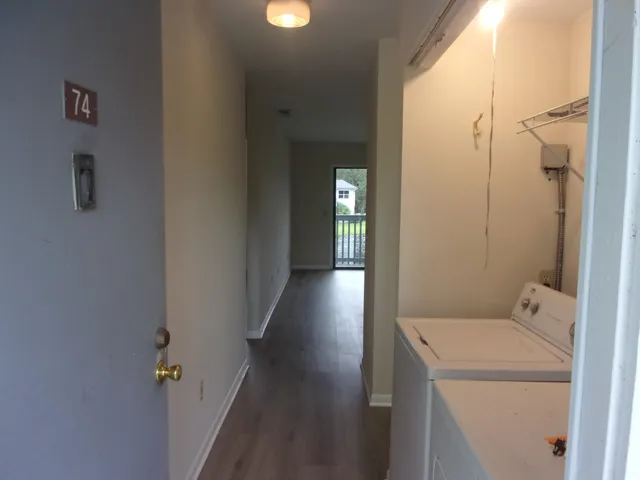 a view of a hallway with wooden floor and a bathroom