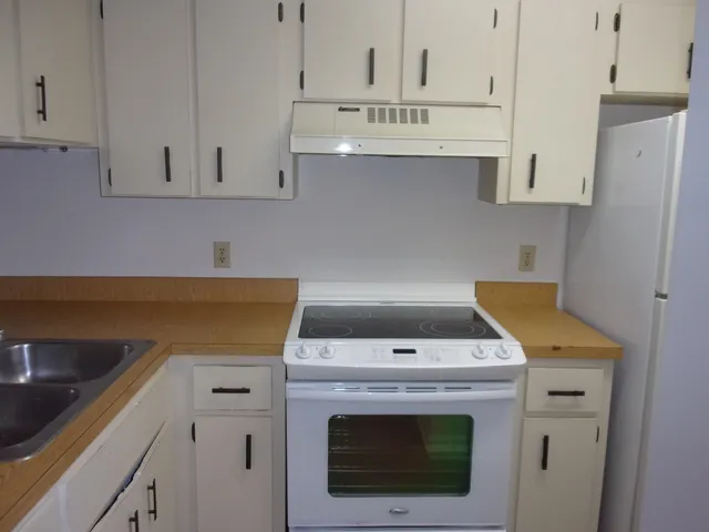a utility room with stainless steel appliances white cabinets and a sink