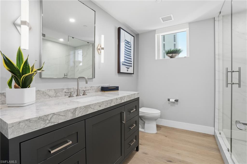 13945 Old Coast Road, Unit 1906 Naples, FL 34110 - Photo 21 of 40 a bathroom with a granite countertop sink a toilet and a large mirror