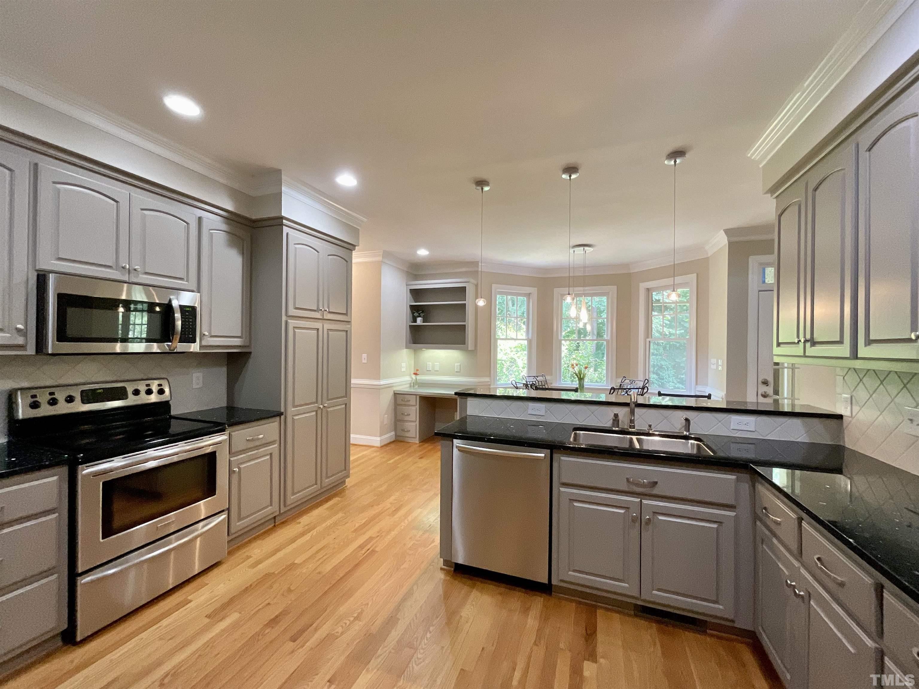4300 Dula Street Durham, NC 27705 - Photo 18 of 42 a kitchen with stainless steel appliances granite countertop wooden cabinets a sink a stove a microwave and wooden floors