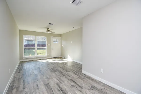 a view of an empty room with wooden floor and a window