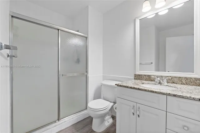 a bathroom with a granite countertop sink toilet and shower