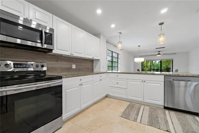 a kitchen with stainless steel appliances granite countertop a stove a sink and a microwave