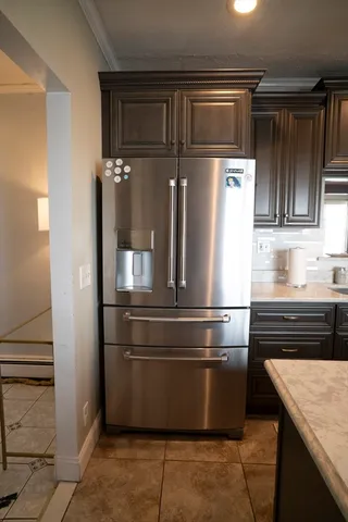 a view of a refrigerator in kitchen and an empty room