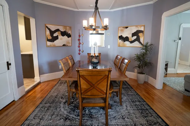 a dining room with furniture wooden floor a rug and a chandelier