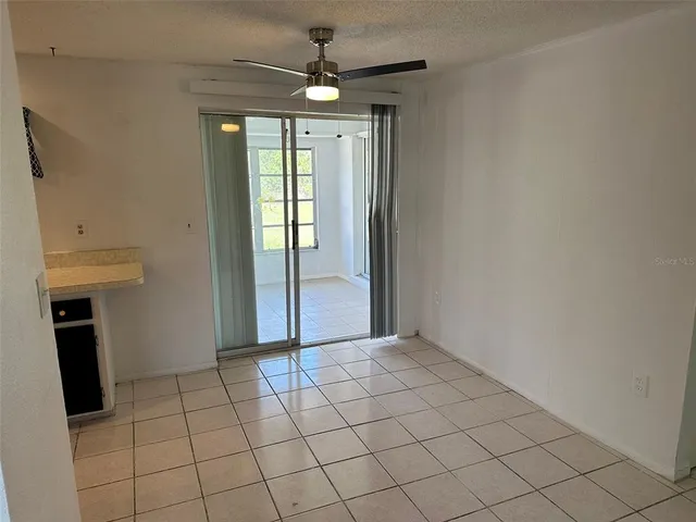 a view of an empty room with window and chandelier fan