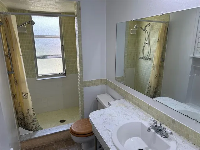 a bathroom with a sink a toilet and shower