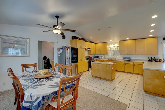 a dining room with stainless steel appliances kitchen island granite countertop a dining table chairs and a refrigerator