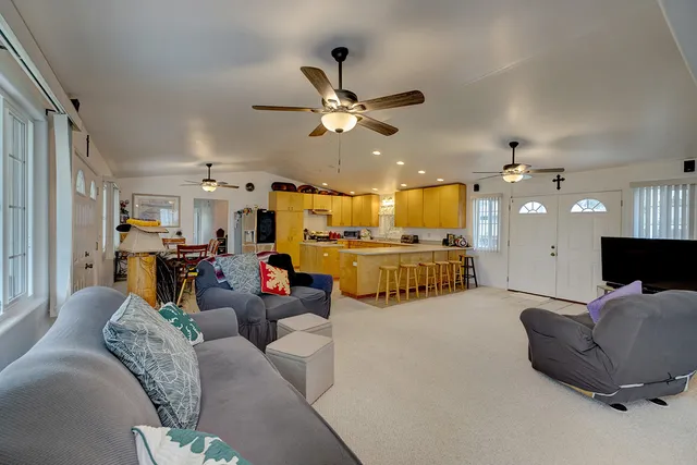 a living room with furniture kitchen view and a chandelier