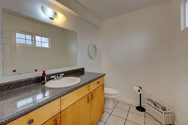 a bathroom with a granite countertop sink a toilet and a mirror