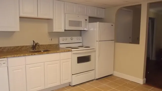 a kitchen with granite countertop white cabinets and white appliances