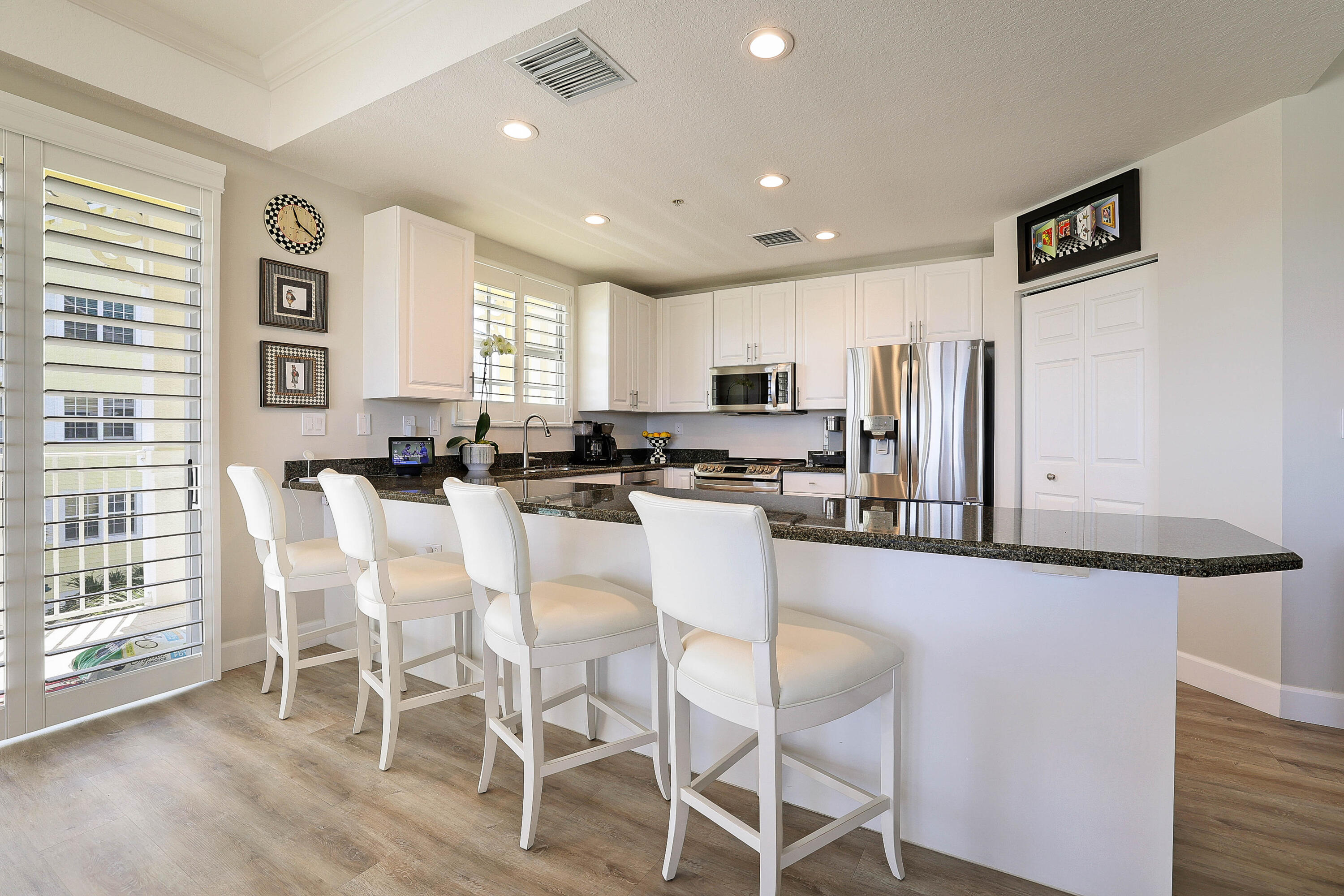 810 Juno Ocean Walk, Unit 401B Juno Beach, FL 33408 - Photo 19 of 57 a kitchen with stainless steel appliances kitchen island granite countertop a stove a refrigerator a white table and chairs with wooden floor