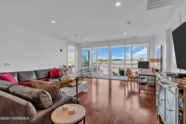 a living room with furniture kitchen view and a wooden floor
