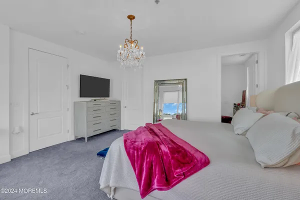 a bedroom with a bed chandelier and a flat screen tv