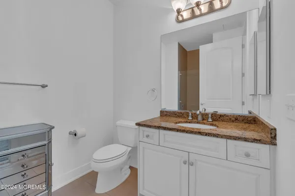 a bathroom with a granite countertop toilet sink and mirror