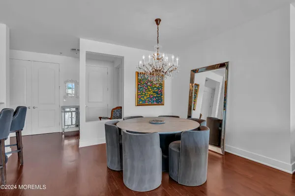 a dining room with chandelier and wooden floor
