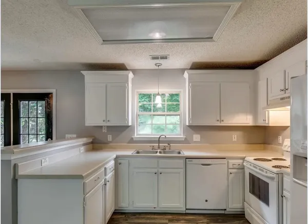 a kitchen with granite countertop a sink stainless steel appliances and white cabinets