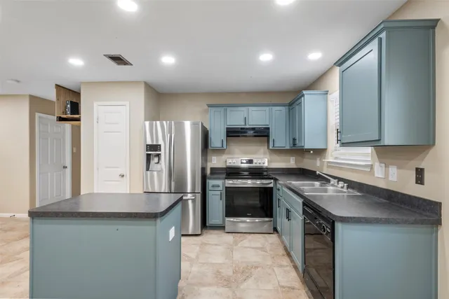 a kitchen with stainless steel appliances granite countertop a stove refrigerator sink and microwave