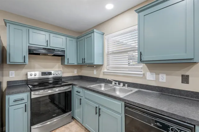 a kitchen with granite countertop a stove sink and cabinets