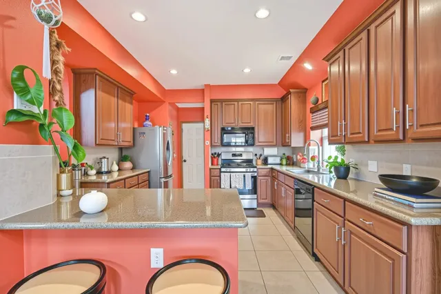 a kitchen with stainless steel appliances kitchen island granite countertop a stove top oven a sink dishwasher and cabinets with wooden floor