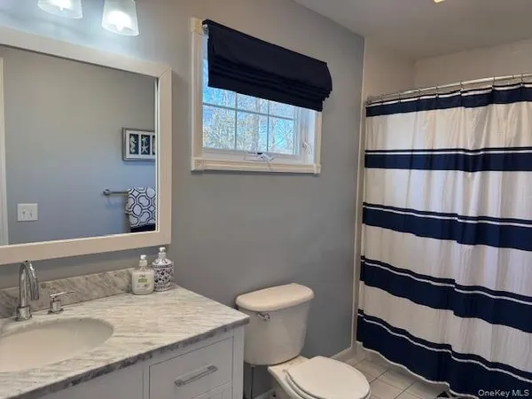 a bathroom with a sink a toilet a window and a mirror