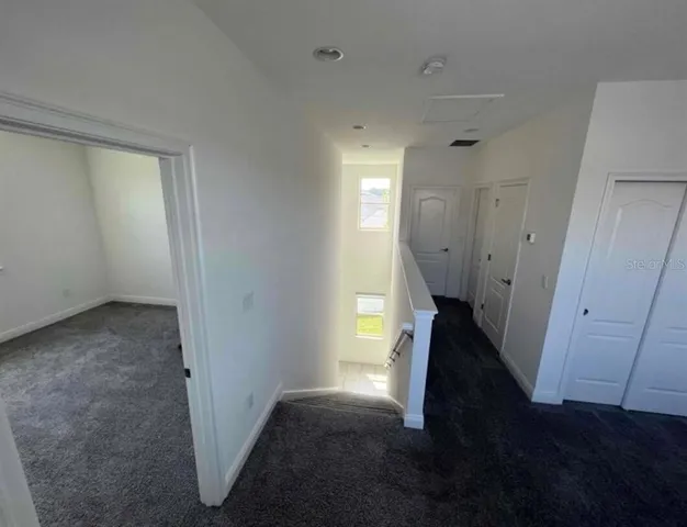 a view of a hallway to a livingroom with wooden floor and staircase