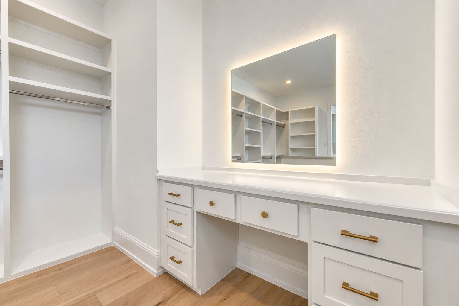 2309 Hollister Road Houston, TX 77080 - Photo 24 of 47 A dedicated dressing vanity elevates the custom walk-in closet with a beautifully integrated countertop, abundant drawer storage, sophisticated brass hardware, and an illuminated mirror. Surrounded by thoughtfully designed shelving and hanging space, this boutique-inspired detail creates a polished spot for getting ready while bringing the ease and indulgence of a private dressing room home.