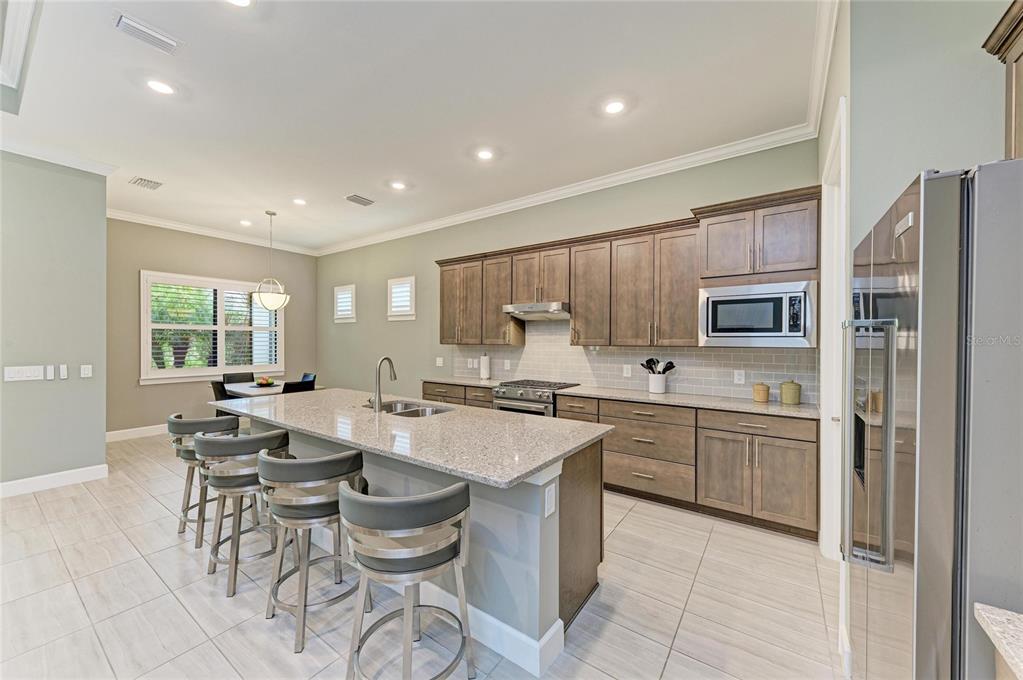 17631 Colebrook Circle Lakewood Ranch, FL 34202 - Photo 23 of 85 a kitchen with stainless steel appliances granite countertop a stove top oven a sink dishwasher a dining table and chairs with wooden floor