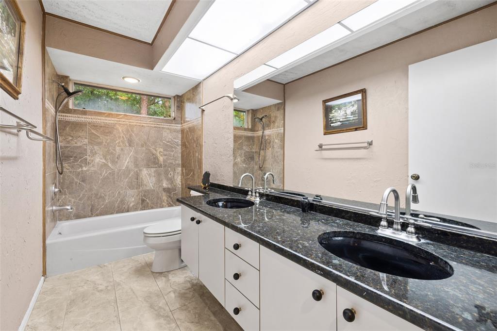 1343 Ranchero Drive Sarasota, FL 34240 - Photo 50 of 68 a bathroom with a granite countertop sink a toilet a mirror a bathtub and shower