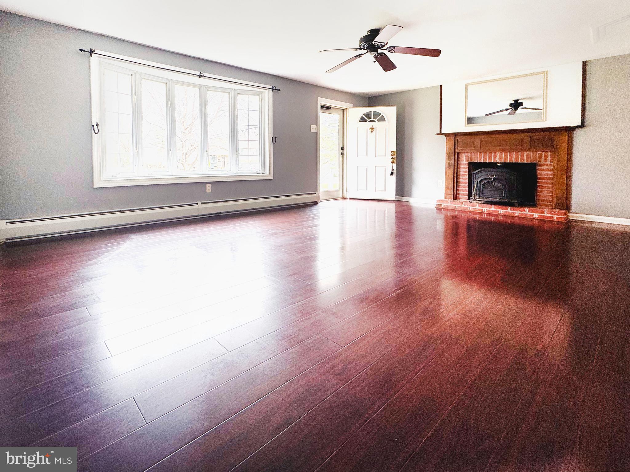 1228 Clyde Road Warminster, PA 18974 - Photo 3 of 19 an empty room with wooden floor fireplace and windows