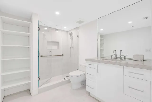 a bathroom with a granite countertop sink a toilet and a shower