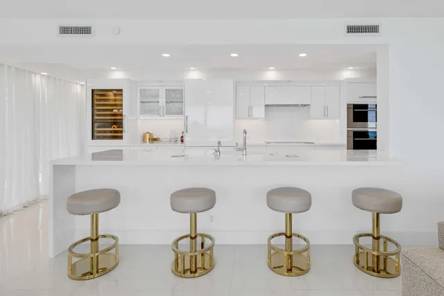 a kitchen with stainless steel appliances granite countertop a sink white cabinets and chairs