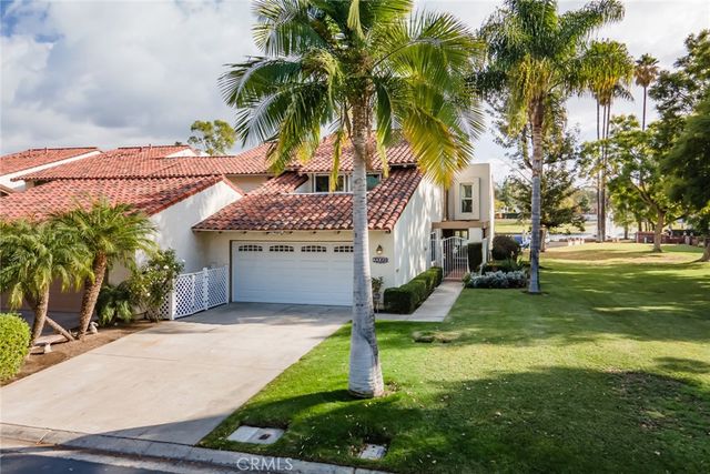 a front view of a house with garden and palm trees