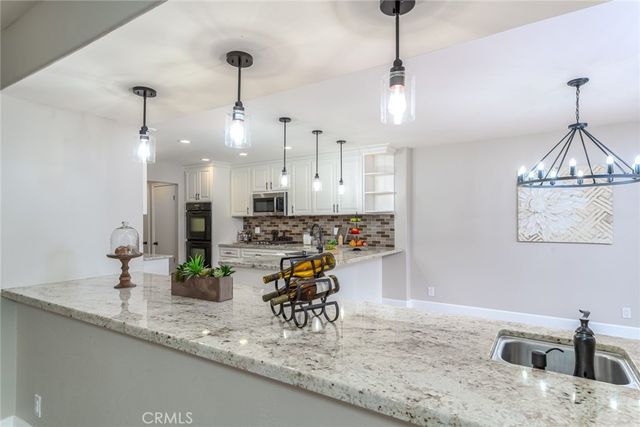 a kitchen with granite countertop a sink a counter space appliances and cabinets