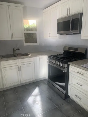 a kitchen with granite countertop white cabinets stainless steel appliances and sink